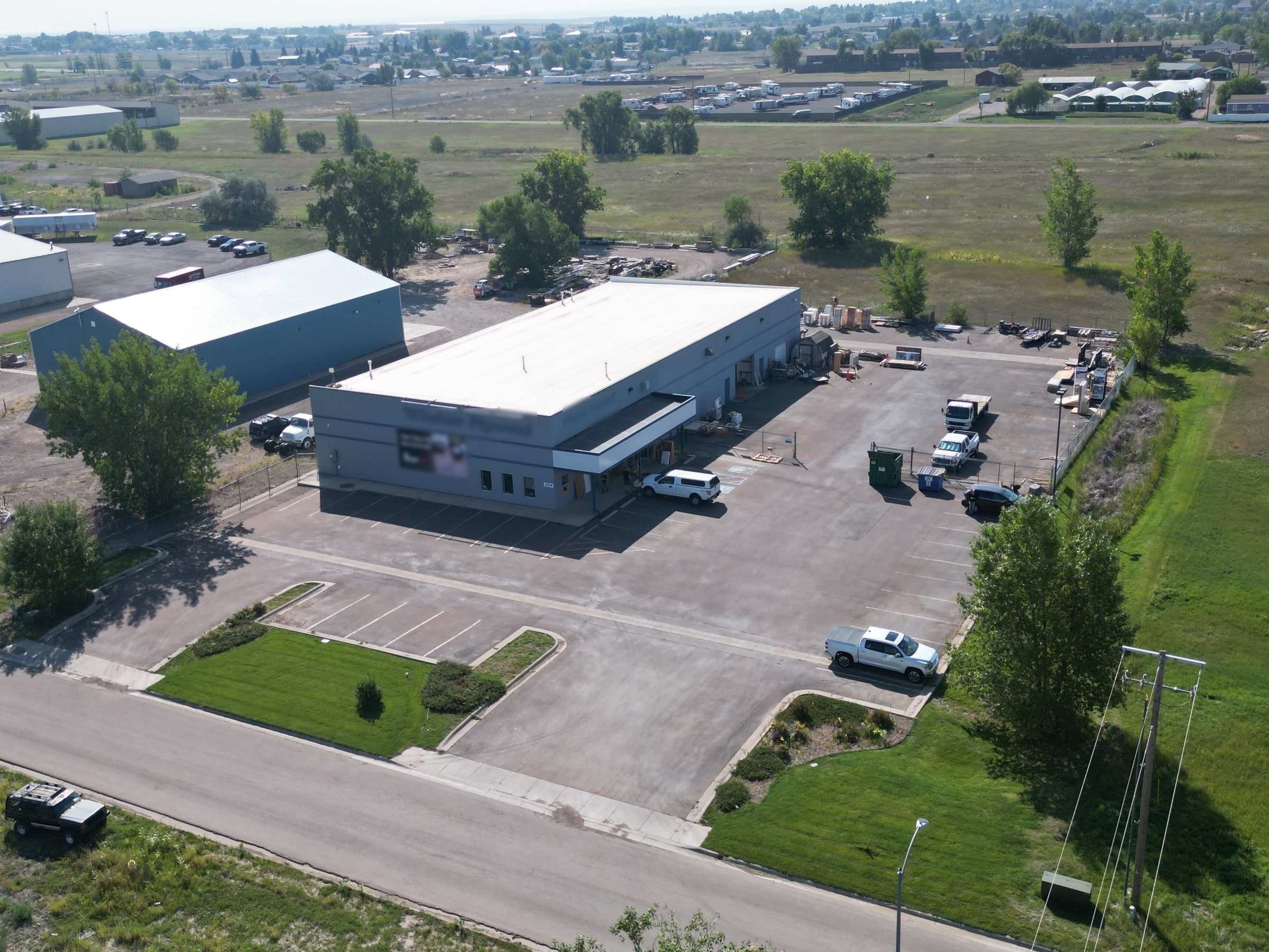 Aerial view of a warehouse with front office, yard, and paved parking in Great Falls